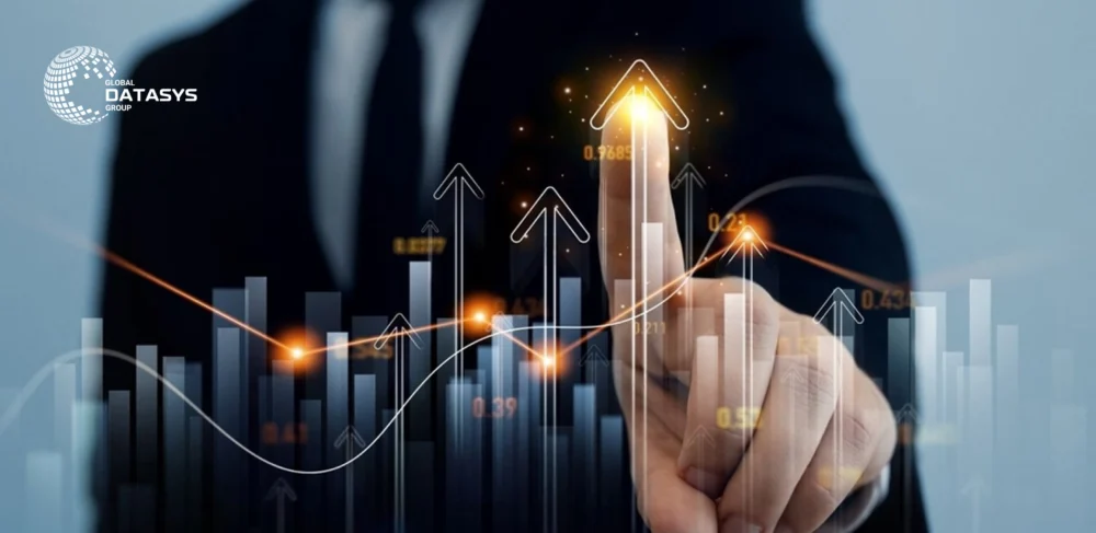 Business professional in a suit pointing to a glowing upward arrow on a virtual chart, representing data growth and rising metrics. Bar graphs, arrows, and glowing data points highlight SaaS growth trends. Global Datasys Group logo is visible in the top-left corner.